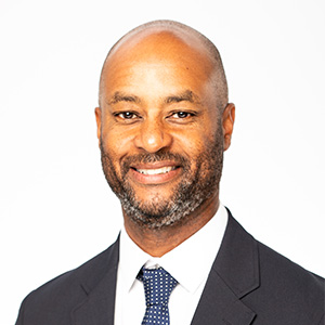 Anthony Goulbourne wearing dark suit, white dress shirt, and a tie.