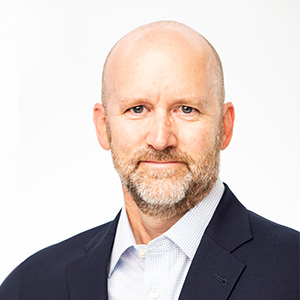 Headshot of Justin Oesterle wearing dark jacket and white dress shirt.